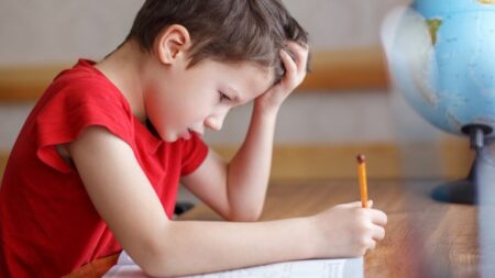 Bub sitzt verzweifelt über einem Heft und hält Stift