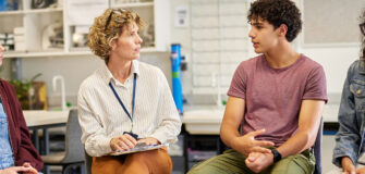 Eine Beraterin spricht mit drei Jugendlichen in einem Raum über Ausbildung und berufliche Perspektiven.