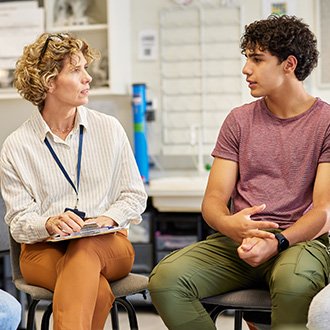 Eine Beraterin spricht mit drei Jugendlichen in einem Raum über Ausbildung und berufliche Perspektiven.