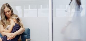Eine Frau hält ein Kind in einem Wartebereich einer medizinischen Einrichtung im Arm.