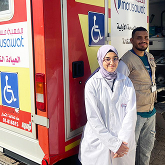 Mitarbeiterin und Mitarbeiter stehen vor der mobilen Klinik im Libanon.