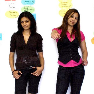 Zwei junge Frauen stehen vor einer weißen Wand mit bunten Moderationskarten.