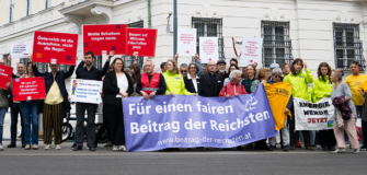 Teilnehmer:innen einer Kundgebung der Allianz für einen fairen Beitrag der Reichsten vor dem Bundeskanzleramt mit Transparenten zur Erbschaftssteuer und Vermögensbesteuerung.