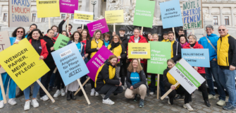 Mitarbeiter:innen von Caritas, Diakonie, Hilfswerk, Rotem Kreuz und Volkshilfe stehen mit Protestschildern vor dem österreichischen Parlament und fordern eine Pflegereform sowie bessere Rahmenbedingungen für Pflege und Langzeitpflege.