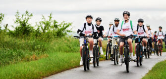 Gruppe von Kindern und Jugendlichen auf Fahrrädern bei der Tour de Chance der Volkshilfe auf einer Landstraße
