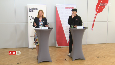 Nora Tödtling-Musenbichler und Erich Fenninger bei einer Pressekonferenz von Caritas und Volkshilfe. Beide stehen an Rednerpulten vor Roll-Ups der Organisationen.