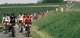 Lange Kolonne von Radfahrer*innen der Tour de Chance auf einem Radweg zwischen Feldern im Südburgenland. Gemeinsam setzen sie ein Zeichen gegen Kinderarmut in Österreich.
