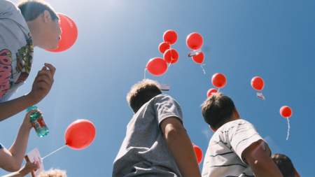 Mit roten Ballons und Wunschkarten senden Kinder ihre Botschaften für eine gerechtere Zukunft in den Himmel.