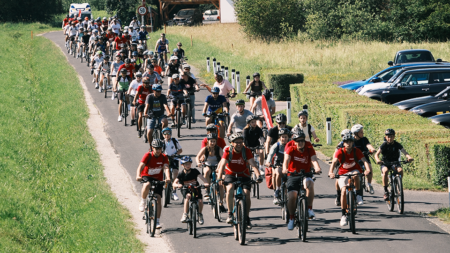 Ein großer Fahrradkonvoi bewegt sich auf einer Landstraße durch die burgenländische Landschaft.