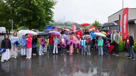 Kinder und Unterstützer*innen empfangen die Tour de Chance 2026 trotz Regen vor der Volksschule Hörzendorf in Kärnten.