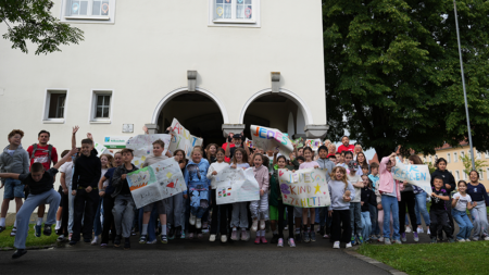 Großes Gruppenfoto vor der Volksschule Plenklberg in Steyr mit den Transparenten