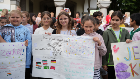 Schülerinnen der Volksschule Riedau präsentieren ihre selbst gestalteten Plakate und Gedanken zu Kinderarmut und Kinderrechten.