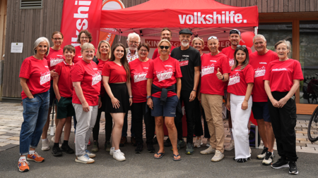 Ehrenamtliche und Helfer*innen der Volkshilfe beim Charity-Bergzeitfahren stehen für ein Gruppenfoto zusammen.