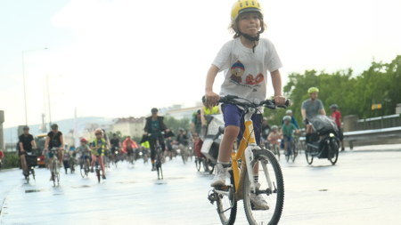 Kind fährt bei der Kidical Mass auf der Straße entlang des Donaukanals.