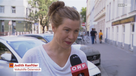 Judith Ranftler von der Volkshilfe Österreich gibt auf einer Straße ein Interview vor einem ORF-Mikrofon.