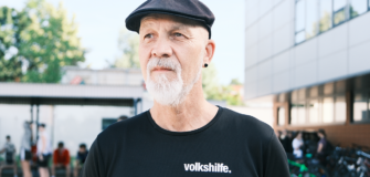 Erich Fenninger steht im Freien vor einem Gebäude und trägt ein schwarzes T-Shirt mit Volkshilfe-Logo.