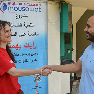 Eine Mitarbeiterin der Volkshilfe begrüßt einen Mitarbeiter der Partnerorganisation Mousawat vor einem Projektstandort im Libanon.