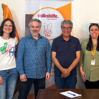 Acht Personen stehen gemeinsam vor einem Banner der Volkshilfe Solidarität.