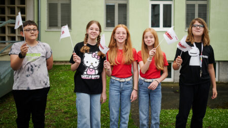 Kinder mit Tour-de-Chance-Fahnen bei einer Schulstation im Burgenland.