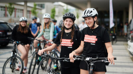 Zwei Schülerinnen mit Fahrrädern und T-Shirts gegen Kinderarmut bei der Tour de Chance 2025.