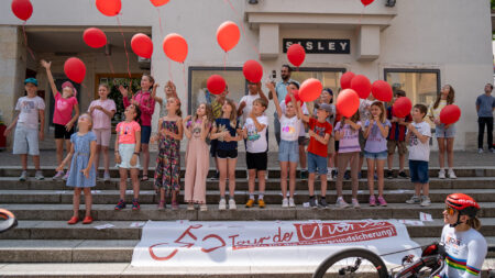 Svetlana Moshkovich vor Schüler*innen mit roten Luftballons beim Tour-de-Chance-Abschluss in Villach.