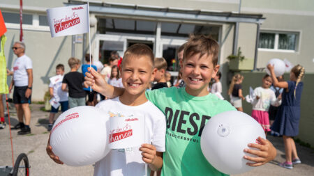 Zwei Schüler der Volksschule Paternion mit Materialien der Tour de Chance 2025.