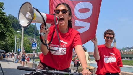 Volkshilfe-Mitarbeiterin mit Megafon bei der Tour de Chance 2025 am Hanuschplatz in Salzburg.